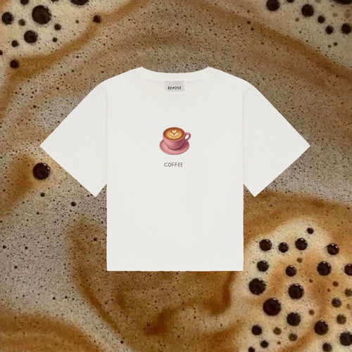 Zdjęcie przedstawia koszulkę COFFEE z filiżanką kawy marki DEPOSE, w kolorze różowym na tle pianki kawy